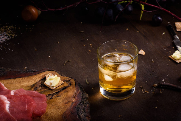 Raw meat, beef steak on wooden table, a glass of whiskey.  - Photo, image