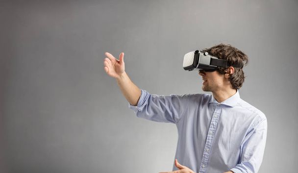 Jeune homme en réalité virtuelle lunettes saisir quelque chose dans l'air. Technologie moderne
. - Photo, image