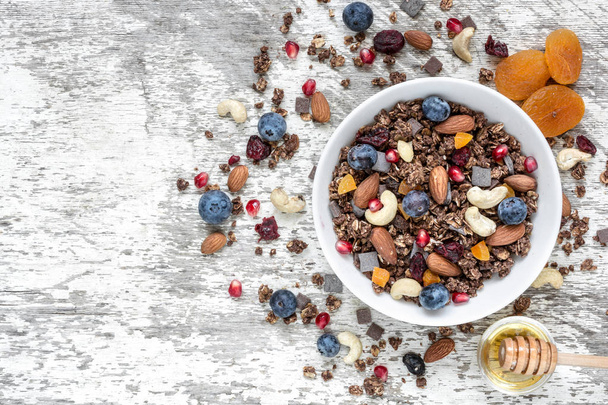 tigela de aveia de chocolate granola ou muesli com nozes, bagas, frutas secas e mel
 - Foto, Imagem