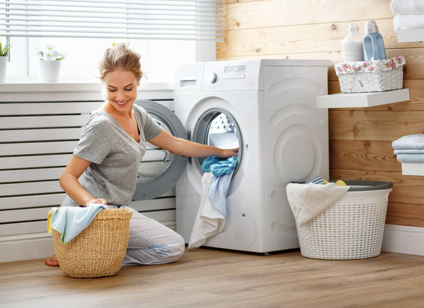 gelukkig huisvrouw vrouw in wasruimte met wasmachine   - Foto, afbeelding