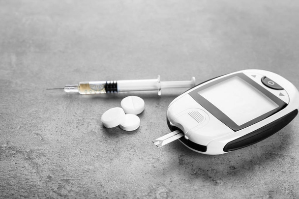 Digital glucometer and medicaments on grey background. Diabetes management - Foto, afbeelding