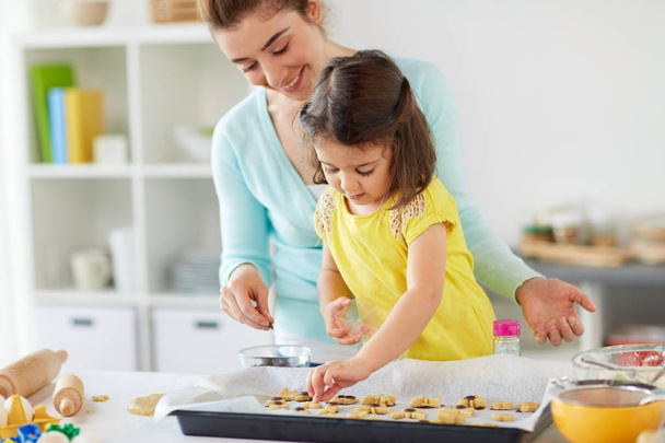 happy mother and daughter making cookies at home - Foto, Imagen