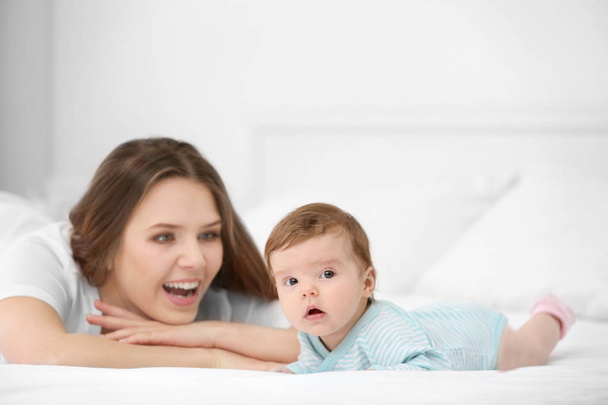 Cute little baby with mother lying on bed at home - Foto, imagen