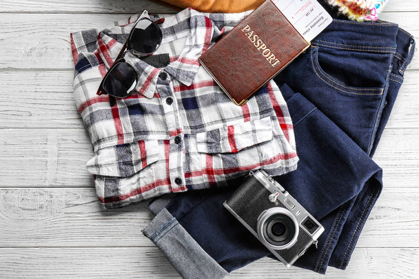 Warm clothes with documents and photo camera on wooden background. Winter vacation concept - Foto, Imagem