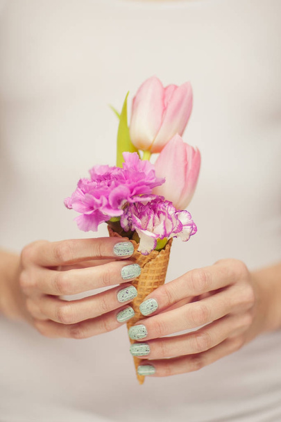 woman hands holding spring flowers in an ice cream cone, sensual studio shot can be used as background - Fotó, kép