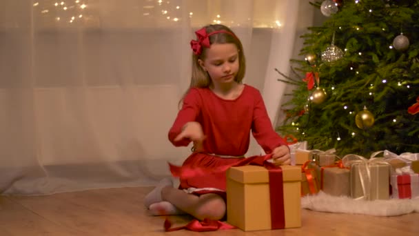 happy girl opening christmas gift at home - Materiał filmowy, wideo