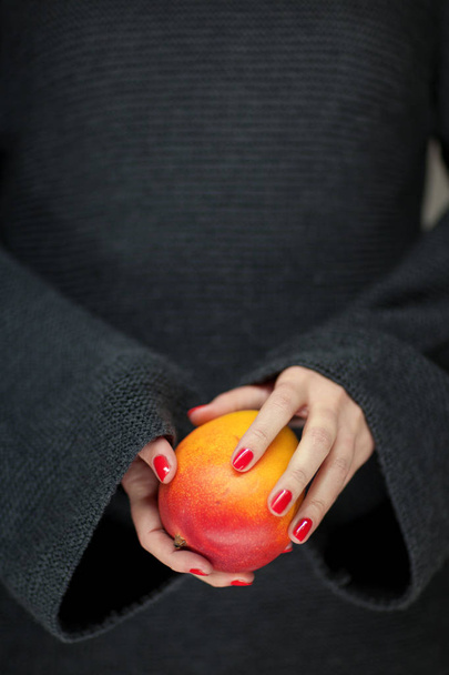Woman hands holding a mango, sensual studio shot can be used as background - Fotoğraf, Görsel