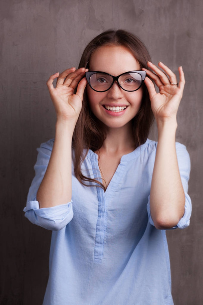 portrait of beautiful happy young woman wearing glasses near grey grunge wall - Фото, зображення