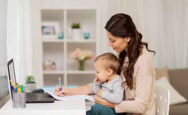 happy mother with baby and papers working at home - Fotó, kép