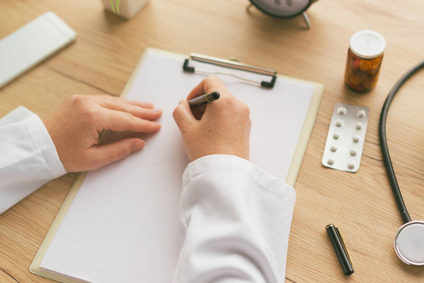 Female doctor writing notes on clipboard paper during medical ex - Photo, Image
