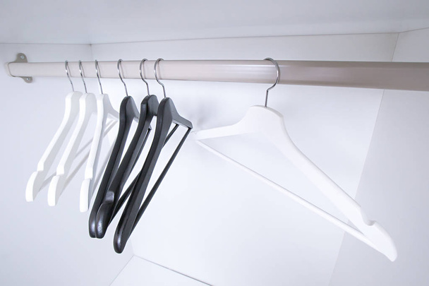 White and black empty clothes hangers, in the wardrobe - Photo, image