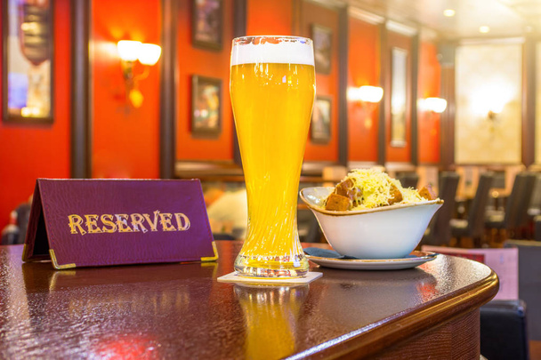 Un verre de bière non filtrée au fromage rusks, une tablette - est réservé sur une table en bois dans le bar du restaurant
. - Photo, image