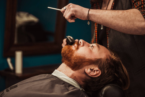A profi fodrász levágja az ügyfél szakállát. Borbélyférfiak - Fotó, kép