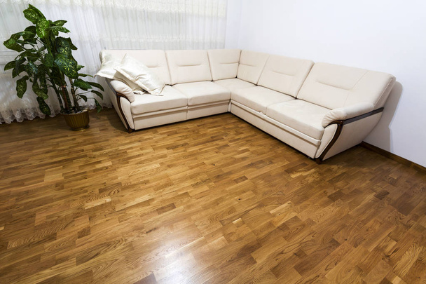 Gran sofá nuevo de color beige en parquet de madera
 - Foto, imagen
