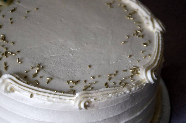 Close up on white cake with golden sprinkles decor - Photo, Image