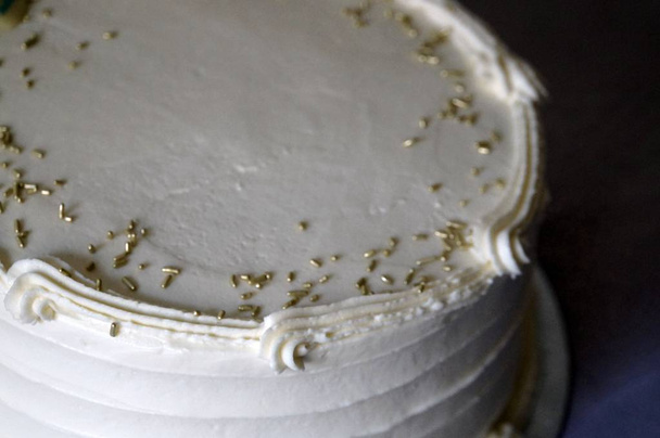 Close-up op witte cake met gouden hagelslag decor - Foto, afbeelding
