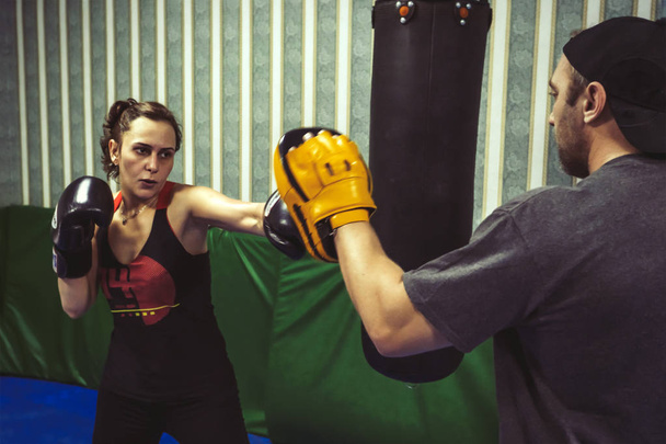 The girl is engaged in boxing with a coach in the gym. - Fotó, kép