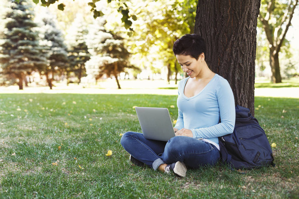 Vrouw zittend op het gras met laptop outdoors - Foto, afbeelding