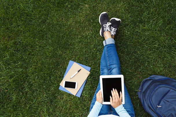 Дівчина з цифровим планшетом на траві
 - Фото, зображення