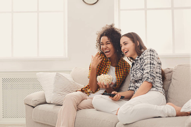 Hymyilevät nuoret naiset katsovat televisiota kotona
 - Valokuva, kuva