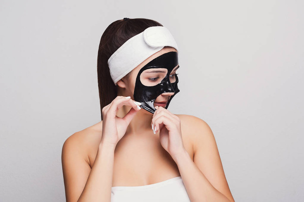 Young girl with purifying black face mask - Фото, изображение