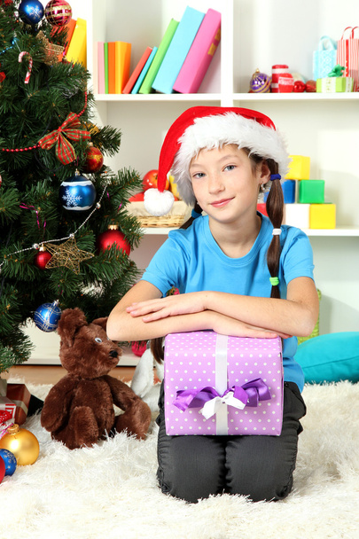 Little girl holding gift box near christmas tree - Foto, Imagem