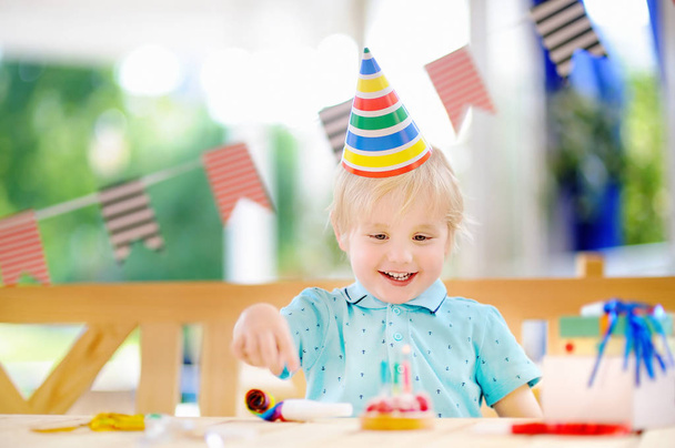 Sevimli küçük çocuk eğleniyor ve doğum günü parti renkli dekorasyon ve kek kutlamak - Fotoğraf, Görsel