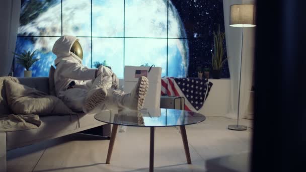 4K Astronaut relaxing in apartment, watching TV and drinking a beer - Video