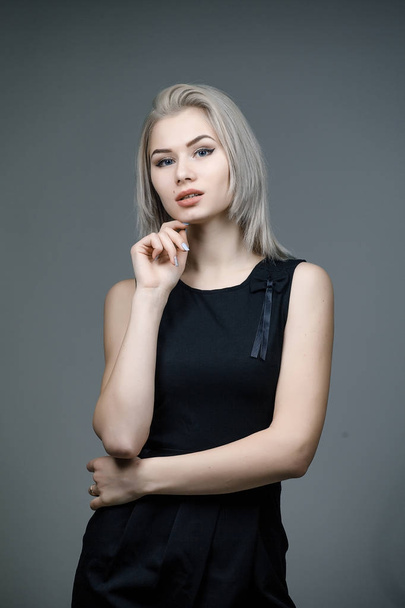portrait of Beautiful blonde woman in back dress on grey background. - Foto, Bild