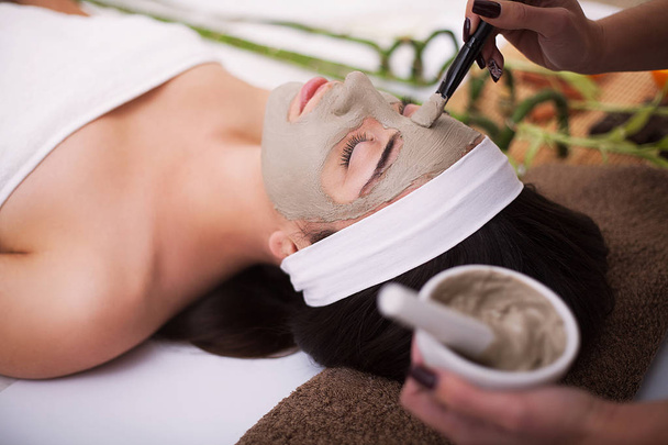 Spa. Beautiful young woman is getting facial clay mask at spa, l - Foto, Bild