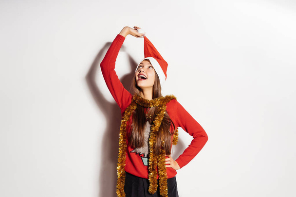 happy young girl takes off a red cap like Santa Claus from his head, waiting for a new year and Christmas - Foto, Imagen
