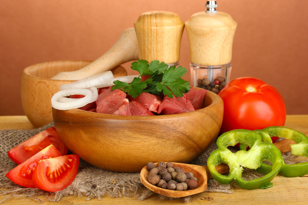 Raw beef meat with herbs and spices on wooden table on brown background - Foto, Imagen