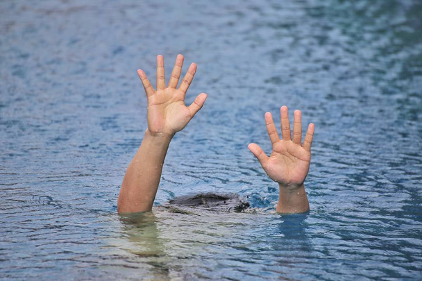 Man drowning in out door swimming pool while swimming alone, raising two hands and asking for help - Photo, Image