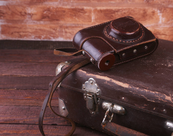 Travel concept with Vintage suitcase old camera on wooden floor. - Valokuva, kuva