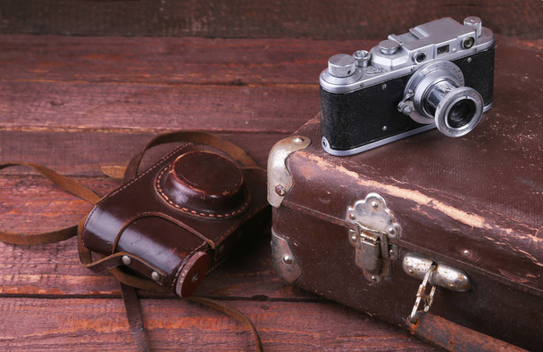 Travel concept with Vintage suitcase old camera on wooden floor. - Foto, imagen