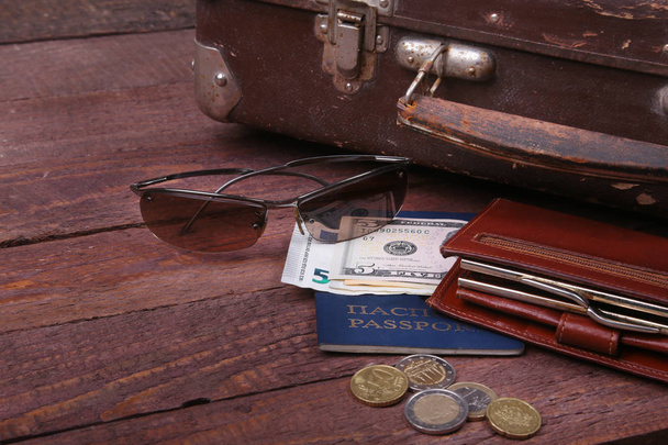 Travel concept with Vintage suitcase, sunglasses, old camera, suede boots, case for money and passport on wooden floor. - Zdjęcie, obraz