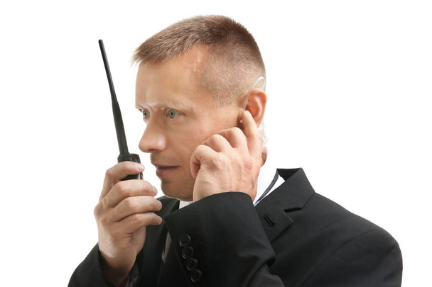 Male security guard using portable radio transmitter on white background - Фото, изображение
