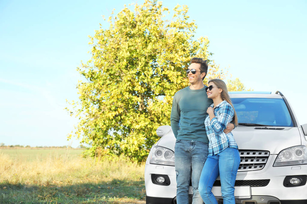 Beautiful young couple standing near car outdoors - Foto, imagen