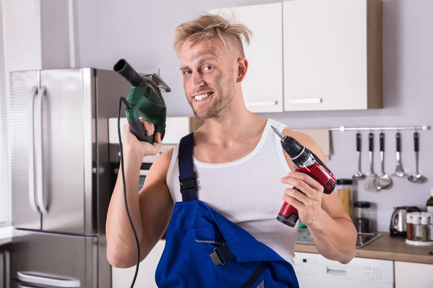 Portrait Of A Confident Technician Holding Electric Drill and Screwdriver
 - Фото, изображение