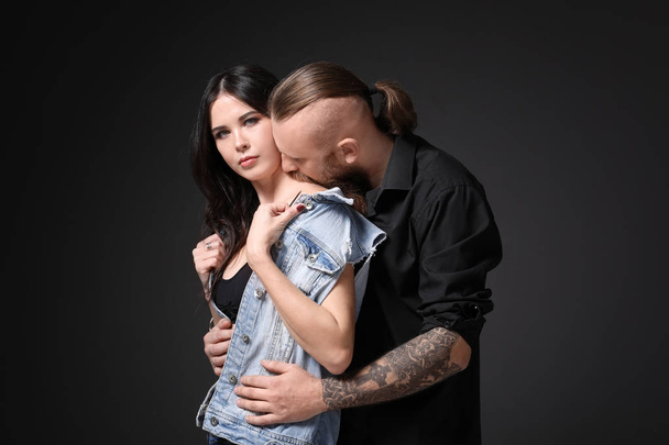 Tattooed man kissing his girlfriend on dark background - Fotó, kép