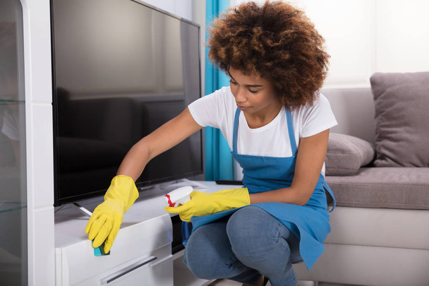 Young Female Janitor Cleaning Furniture With Sponge At Home - Foto, immagini