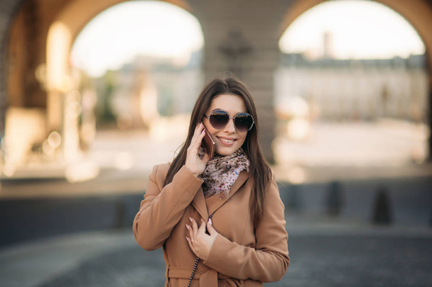 Стильна дівчина в коричневому пальто і шарф з окулярами. Використовуючи телефон у паризькій Франції. Макіяж
 - Фото, зображення