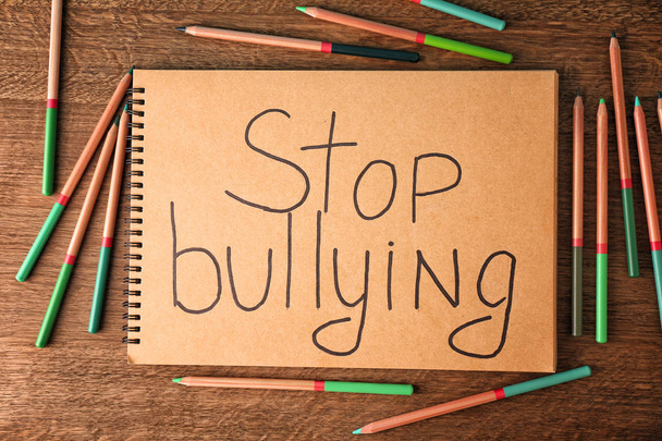 Notebook with text "Stop bullying" on wooden background - Fotó, kép
