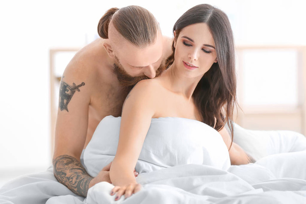 Tattooed man with his girlfriend in bed at home - Foto, Imagem