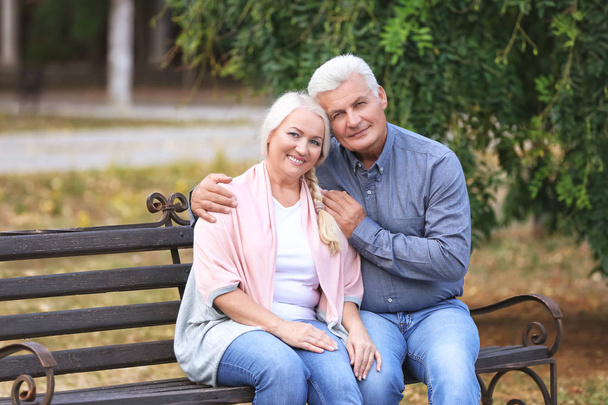 Mature couple sitting on bench outdoors - Foto, afbeelding
