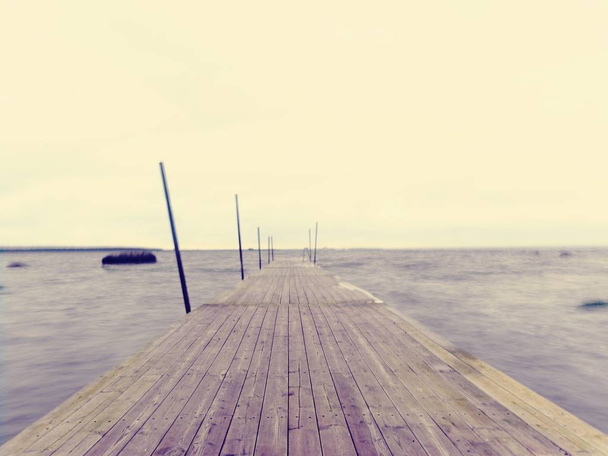 Wet pier in smooth water of sea bay.  Mole anchored with steel poles into bottom - Photo, Image
