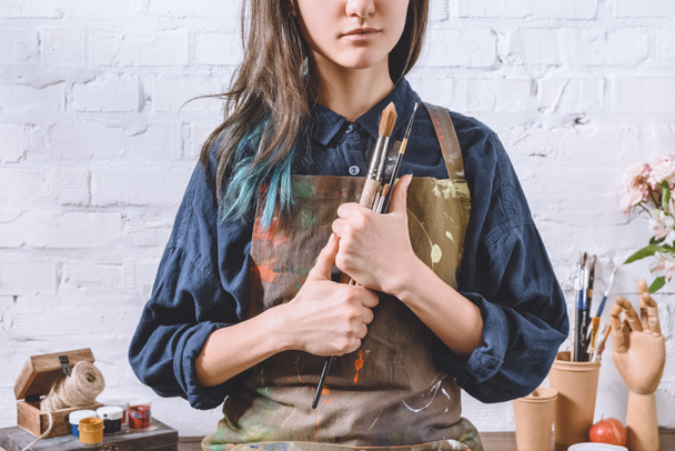 bijgesneden afbeelding van vrouwelijke kunstenaar holding borstels  - Foto, afbeelding