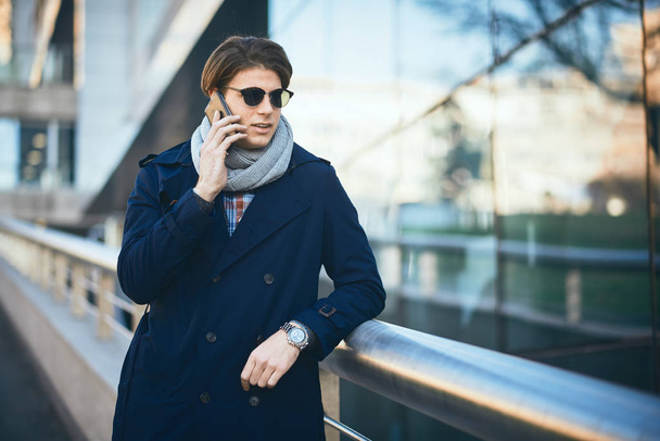 Jovem empresário usando telefone inteligente enquanto está de pé na rua
. - Foto, Imagem