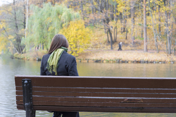 girl sitting alone on a bench in autumn day. - Photo, Image