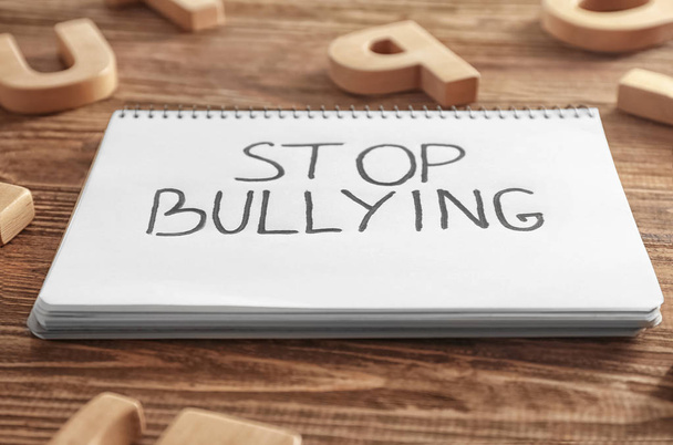 Notebook with text "Stop bullying" on wooden background, closeup - Fotografie, Obrázek